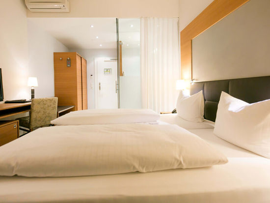 Zwei Kissen und zwei Bettdecken liegen auf einem Doppelbett im Businesszimmer