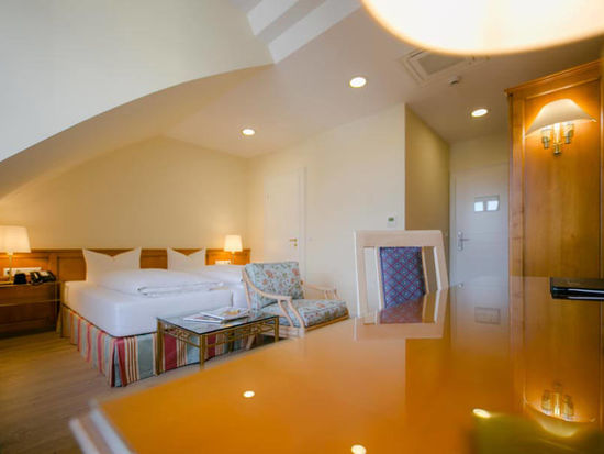 Ein Schreibtisch ein weiches Doppelbett und Sitzgelegenheiten mit den dazu passenden Glastisch haben in diesen Superior Zimmer platz.