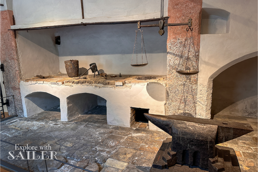 Historic workshop featuring an anvil, scales, and traditional tools at the Hall Mint Museum in Hasegg Castle.