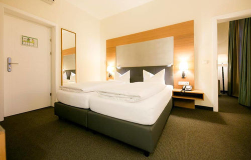 A large double bed stands in a large room with a carpet