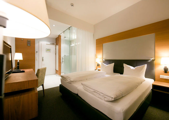 View into the business room of Hotel Sailer with a double bed, a comfortable sofa and a floor lamp