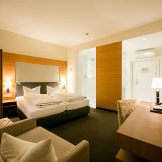 View into the business room of the Hotel Sailer with a double bed, a comfortable sofa and a floor lamp