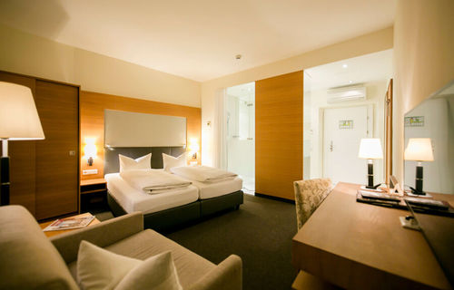 View into the business room of the Hotel Sailer with a double bed, a comfortable sofa and a floor lamp