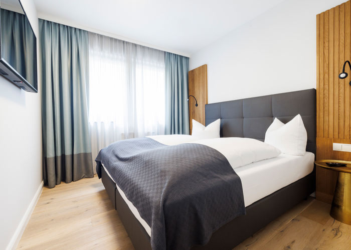 The modern double bed in the bedroom of the Deluxe Plus Apartment.