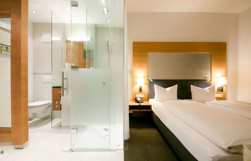 View into the business room of the Hotel Sailer with a double bed and a large bathroom with shower