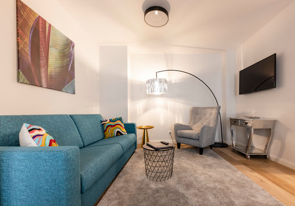 Il moderno soggiorno dell'appartamento Delux XL con divano, tappeto, tavolo e molto altro.