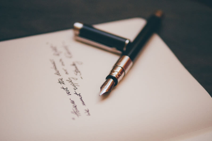 A fountain pen lying on a sheet of paper with something handwritten on it