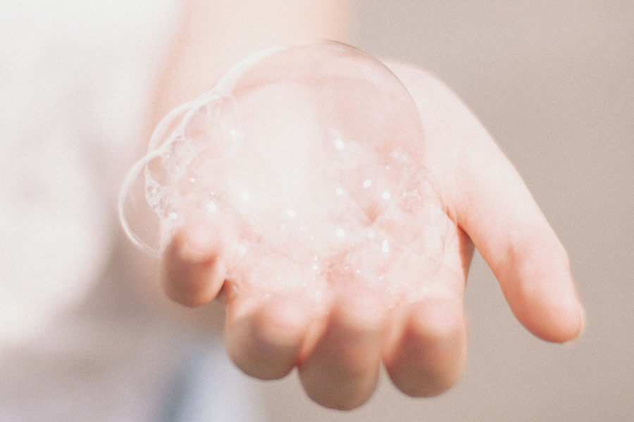 A hand with several soap bubbles on its palm
