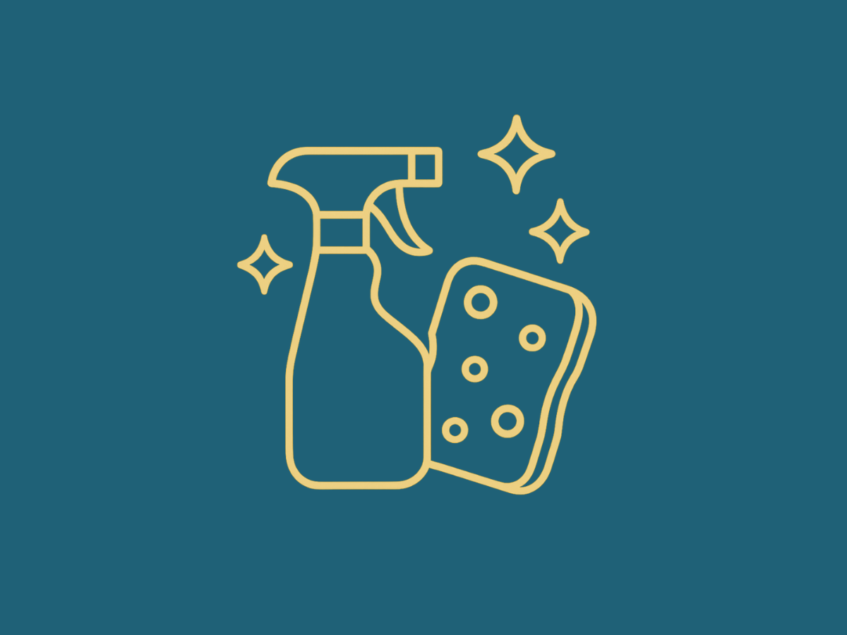 Eine Frau mit Putzhandschuhen die gerade eine weiße Fläche mit Papier und einem Desinfektionsspray putzt