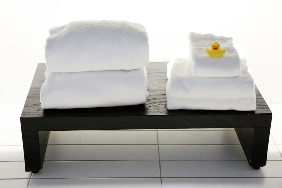 Several clean white towels lie on a black stool