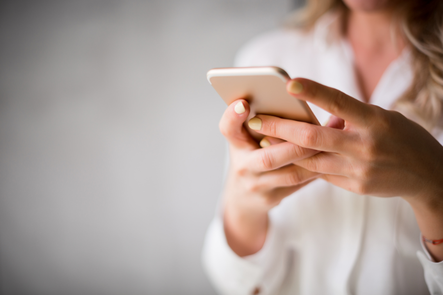 Person hält ein Smartphone in der Hand und tippt.