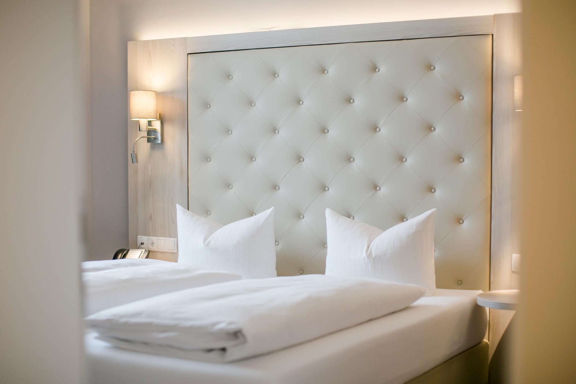 Letto elegante con testata imbottita e morbidi cuscini in una stanza accogliente.