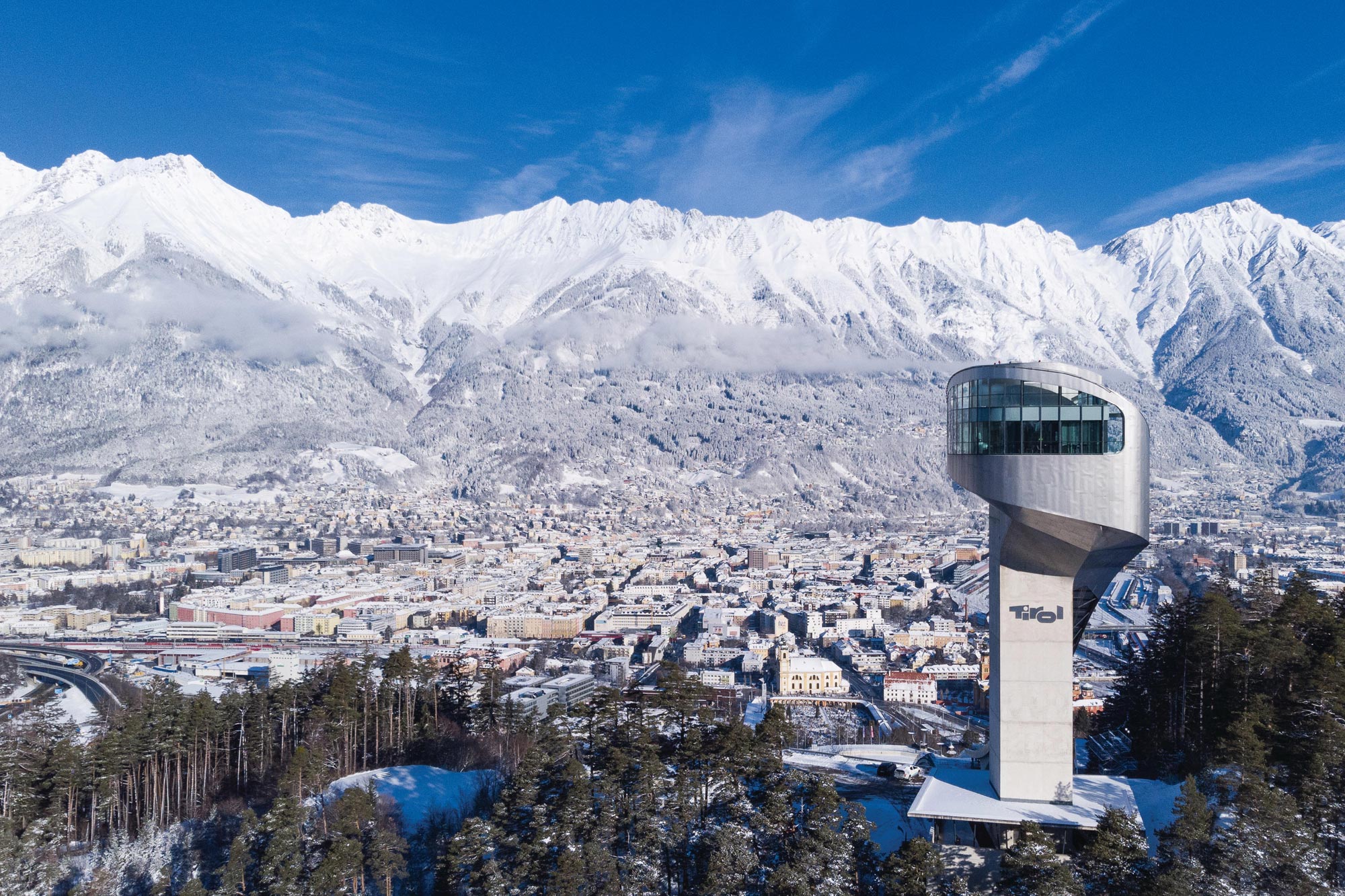 Aussichtsturm mit Blick auf verschneite Berge und die Stadt Innsbruck im Winter.