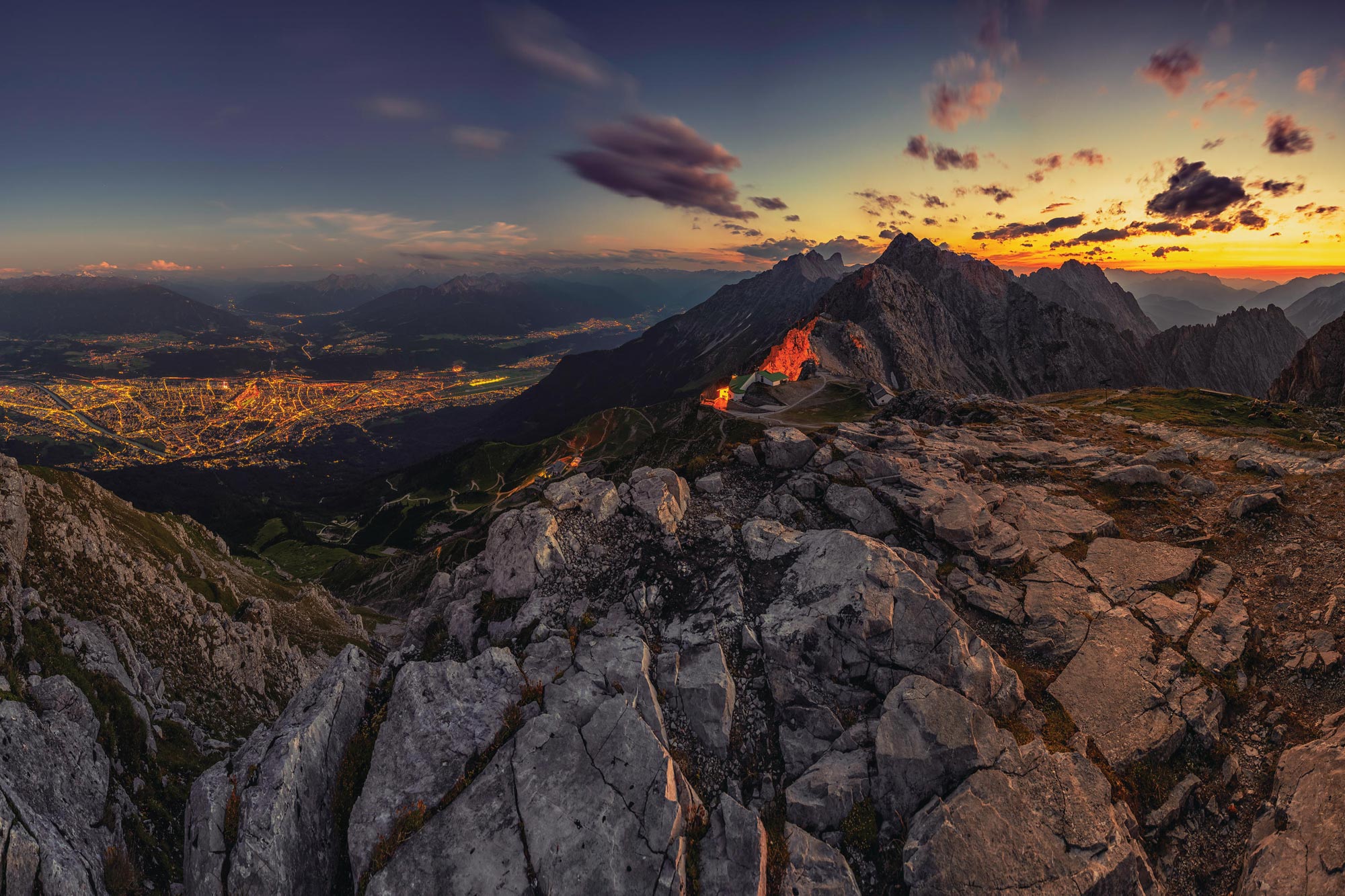 Vista mozzafiato di Innsbruck illuminata al tramonto, circondata da montagne maestose.