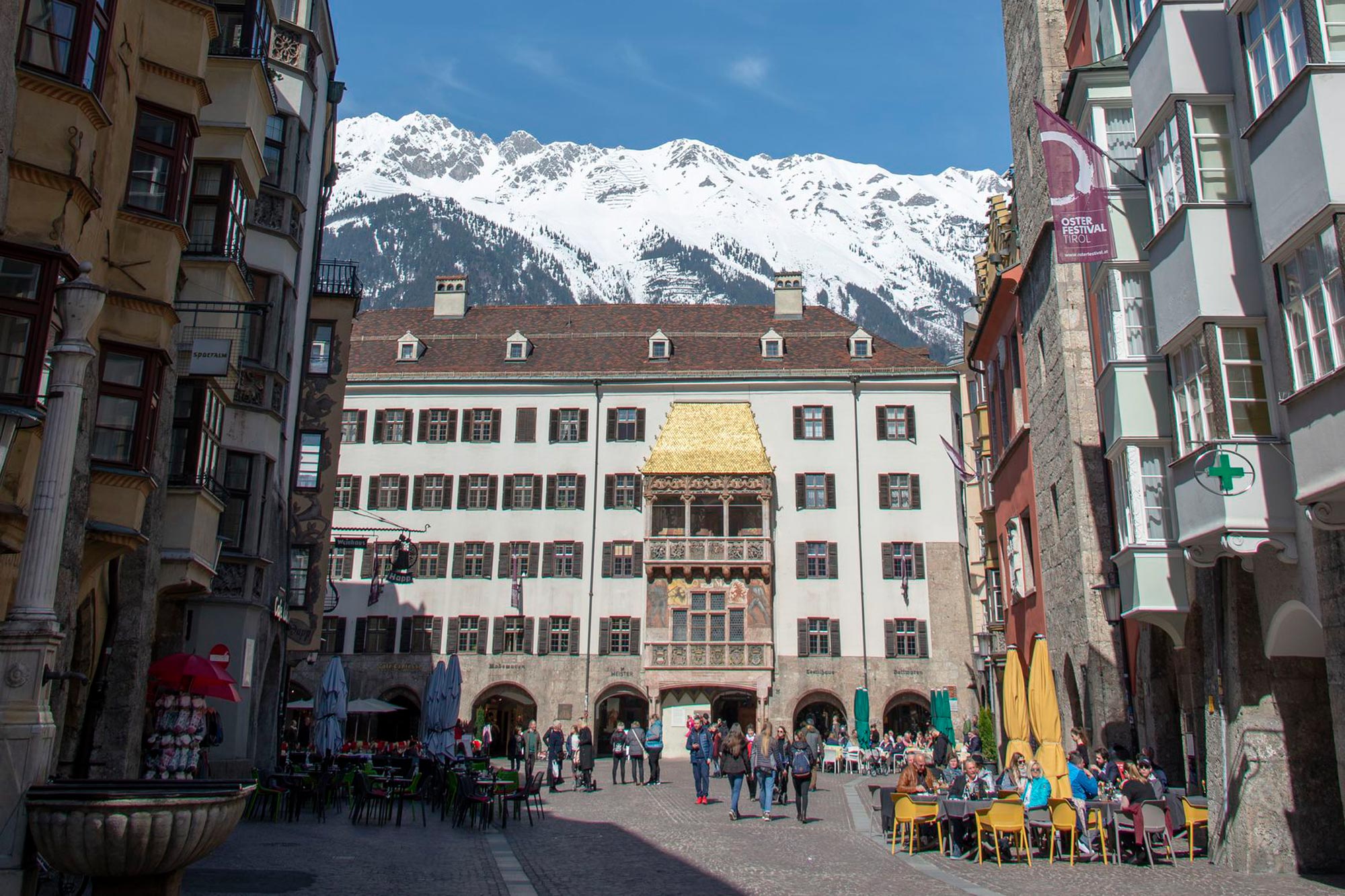 Un centro storico vivace, con il famoso Tettuccio d'Oro e le montagne innevate sullo sfondo.