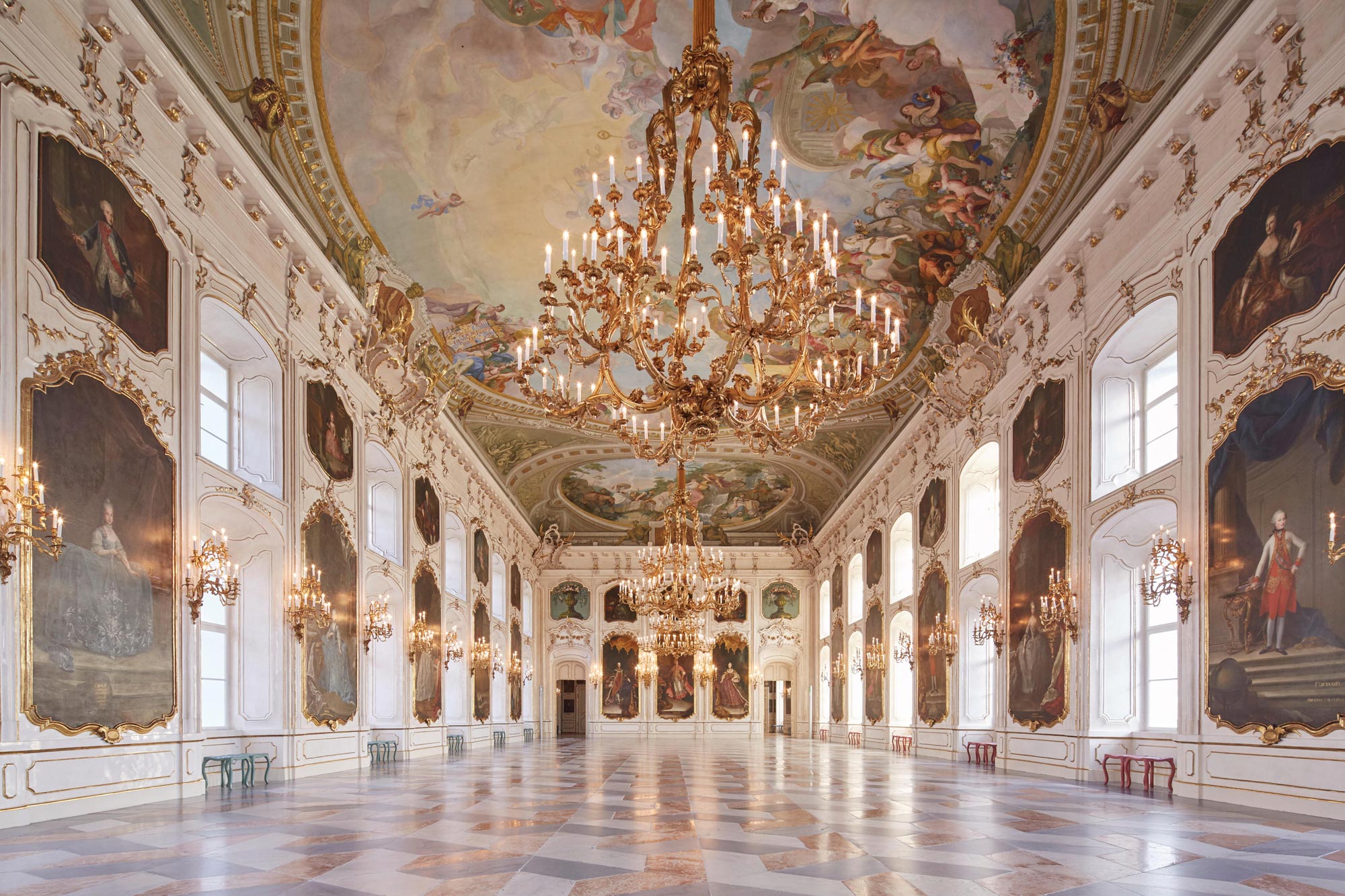 Opulenter Saal mit prächtigen Kronleuchtern und kunstvoll verzierten Deckenfresken.