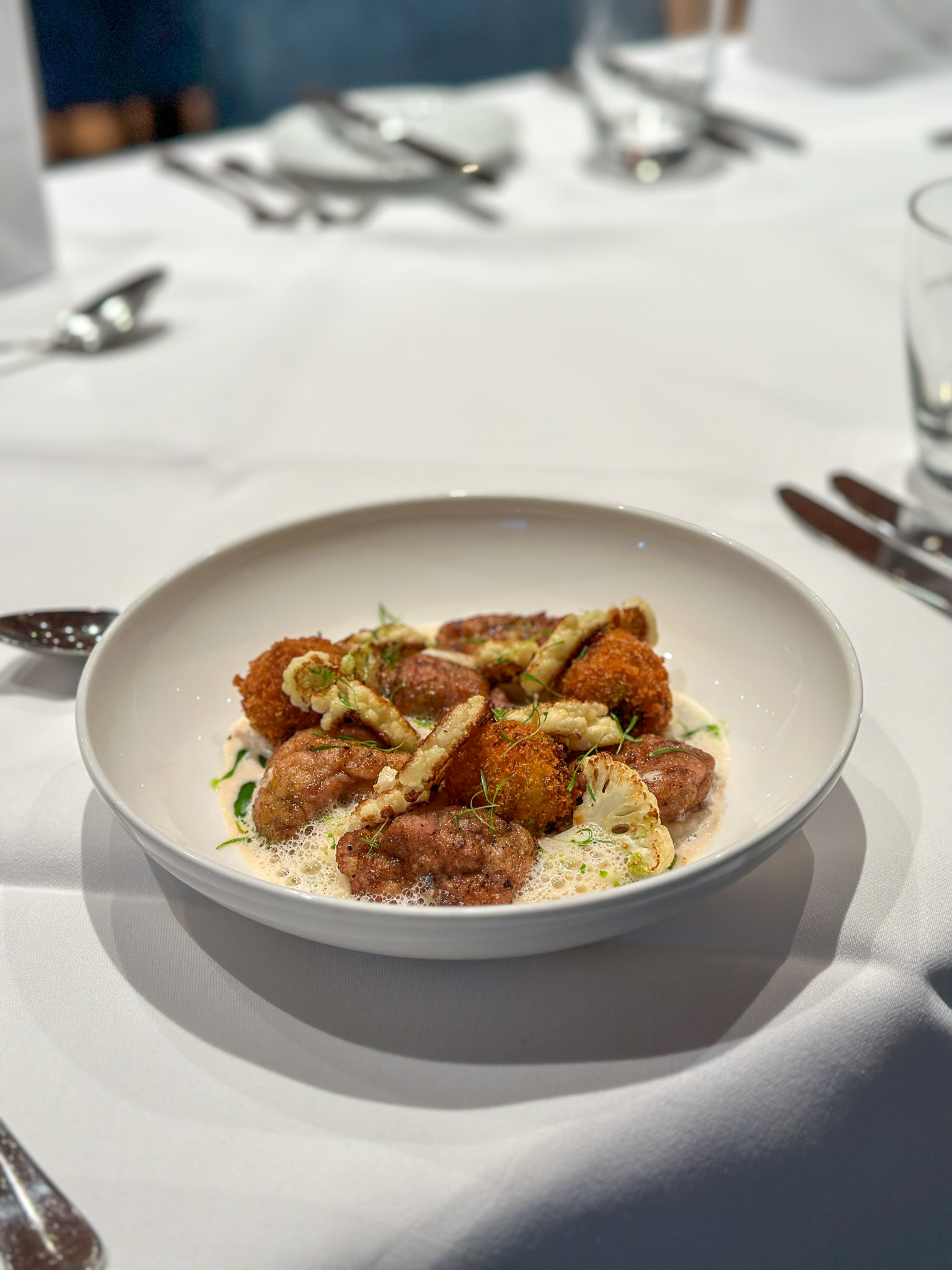 Elegant dish presented on a white plate with a sophisticated sideboard on a table.